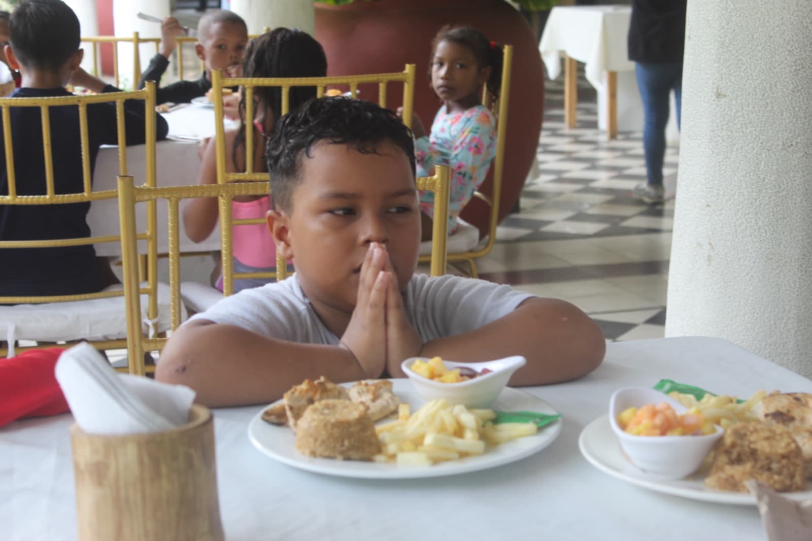 A boy praying before lunch at the table