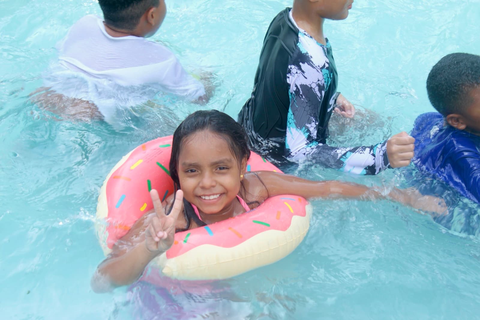 A girl smiling in the pool with a float