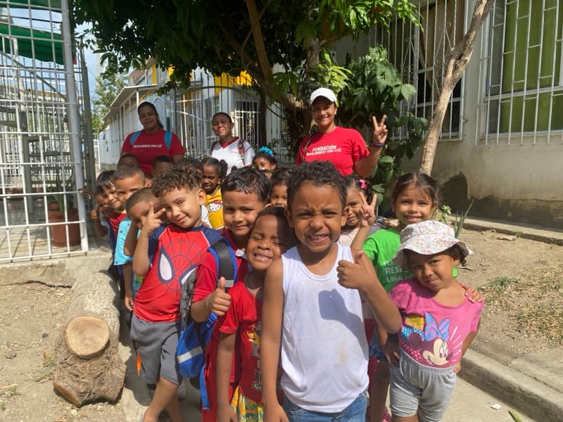 Children smiling and waving outside the Una Luz Foundation school in Cartagena